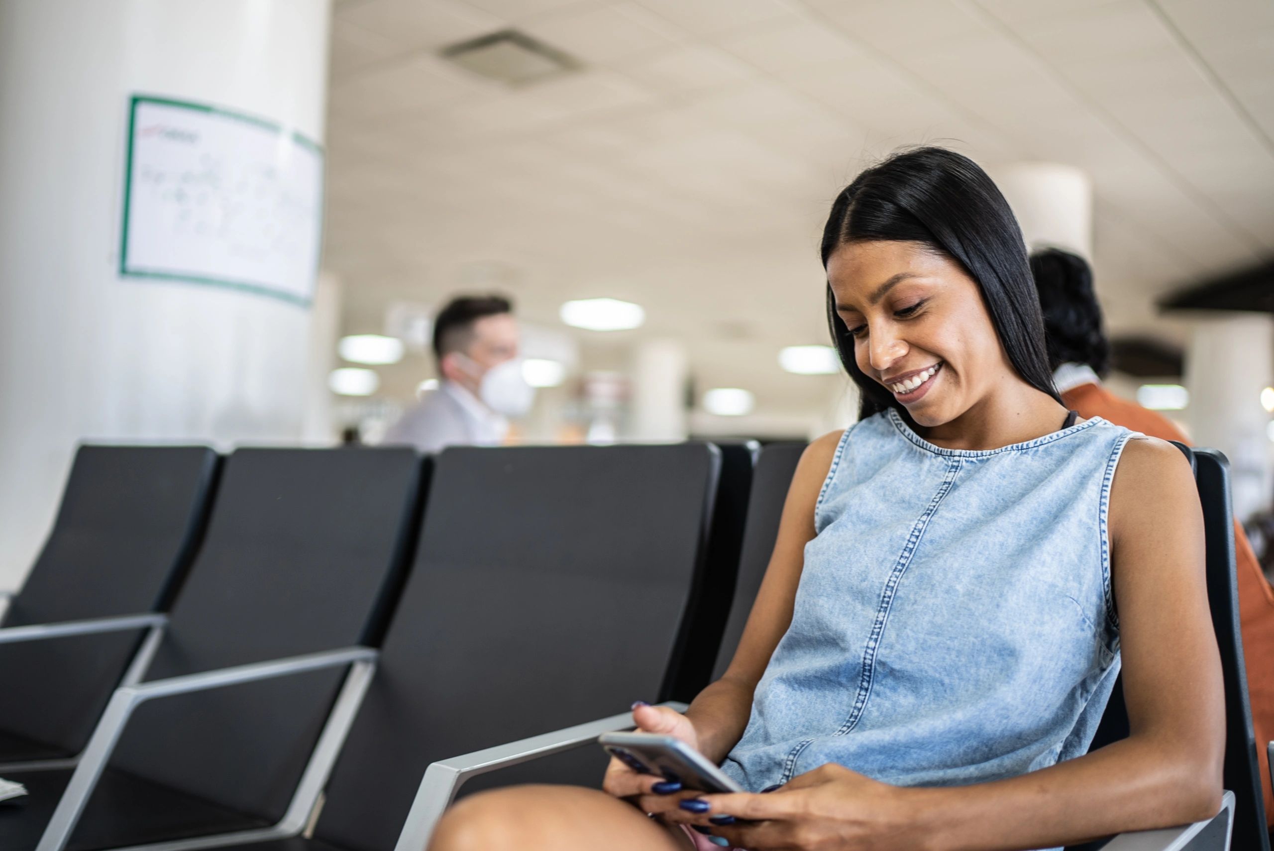 Woman waiting in an airport departure area using a phone